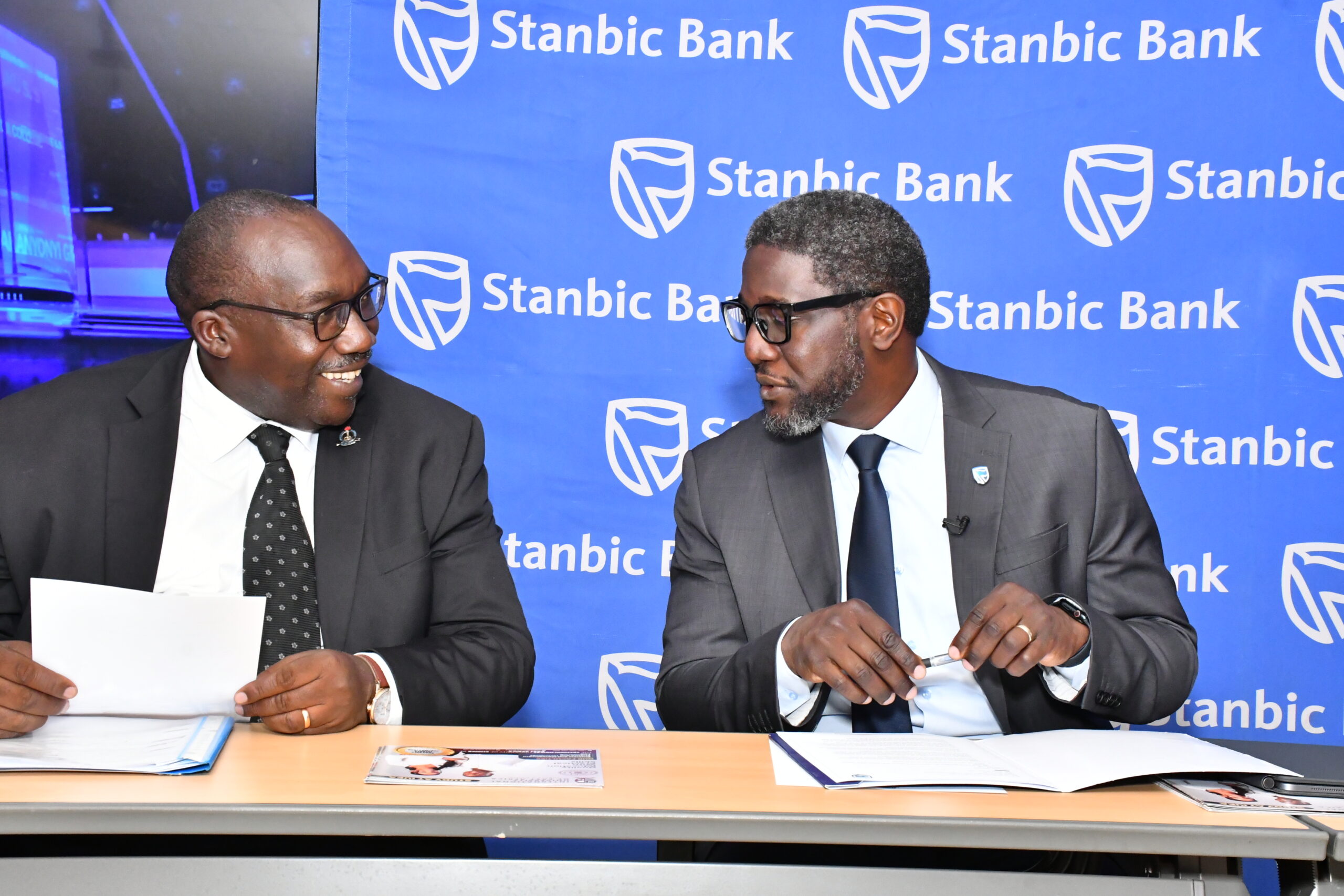 GEORGE~1 George Muteekanga the Ast. Commissioner for Private Schools at Ministry of Education sharing light moments with Sam Mwogeza, the Stanbic Bank Executive Head of Personal banking during the NSC launch at in Kampa (1)